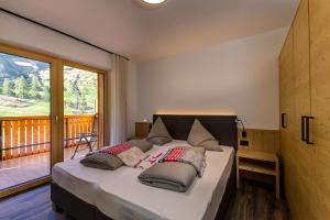 a bedroom with a large bed with a balcony at Apparthotel Marteshof in Pfelders