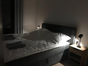 1 cama con sábanas blancas y mesita de noche con lámpara en Bryza Morska, en Świnoujście 66 fotos más