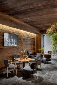 un restaurant avec des murs en bois, des tables et des chaises dans l'établissement HOTEL de LEN, à Cortina dʼAmpezzo