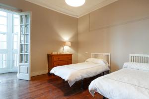 a bedroom with two beds and a dresser and a window at Precioso y cómodo piso en Llanes a 5 de la playa Mercaderes in Llanes