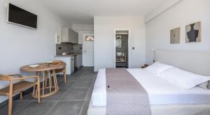 a bedroom with a bed and a table and a kitchen at Hotel Ippocampos Studios in Adamas
