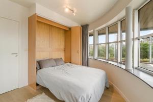 une chambre avec un lit dans une pièce avec des fenêtres dans l'établissement Villa Francois, à Nieuport