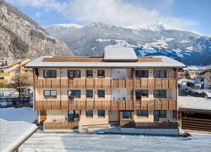 un bâtiment avec des montagnes enneigées en arrière-plan dans l'établissement Appartement Wiere, à Molini di Tures