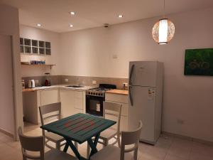 cocina con mesa verde y nevera en Crisálida Puerto Madryn, en Puerto Madryn
