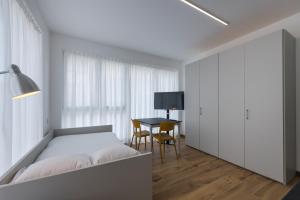 a white bedroom with a bed and a table at Modern Studios Mendrisio in Mendrisio