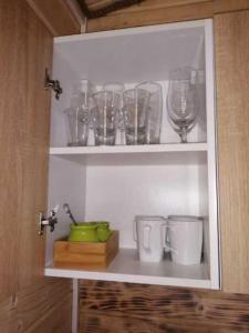 a shelf filled with glasses and wine glasses at Nowy domek letniskowy in Pisz