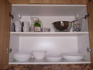 a shelf with bowls and other dishes on it at Nowy domek letniskowy in Pisz