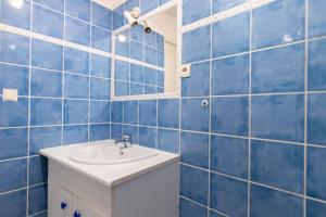 een blauw betegelde badkamer met een wastafel en een spiegel bij Perruche in Saint-Aignan