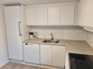 uma cozinha com armários brancos e um lavatório em Feriehuse Hvide Sande em Hvide Sande