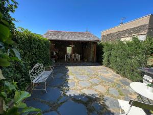 a patio with a bench and a table and chairs at MESON DU BONHEUR in Osséja