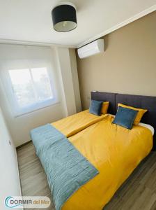 a bedroom with a large yellow bed with blue pillows at Dormir del Mar in La Marina