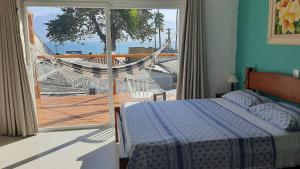 a bedroom with a bed and a hammock on a balcony at RETIRO DA VILA , você no coração de Ilhabela in Ilhabela