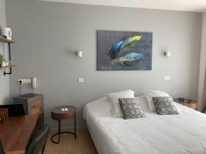 a bedroom with a white bed and a painting on the wall at Hôtel des Argousiers in Ambleteuse