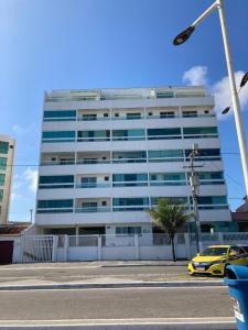 un edificio con un coche amarillo aparcado delante de él en Duplex da Praia Grande, en Arraial do Cabo