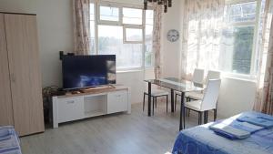 ein Wohnzimmer mit einem TV und einem Tisch mit Stühlen in der Unterkunft Prima Guest House 2 in Sweti Konstantin
