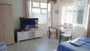 a living room with a television and a table with chairs at Prima Guest House 2 in St. St. Constantine and Helena