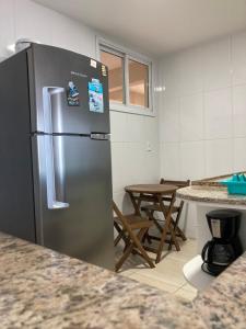 a stainless steel refrigerator in a kitchen with a table at Duplex da Praia Grande in Arraial do Cabo
