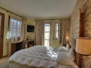 una camera da letto con un grande letto bianco e finestre di Hotel Bait de Angial a Livigno