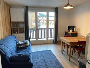 a living room with a blue couch and a table at Location studio plein centre Les Carroz in Les Carroz d'Araches