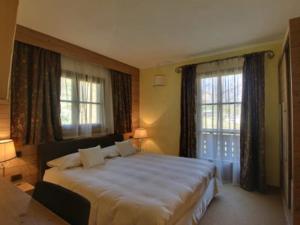 1 dormitorio con 1 cama grande y 2 ventanas en Hotel Bait de Angial, en Livigno