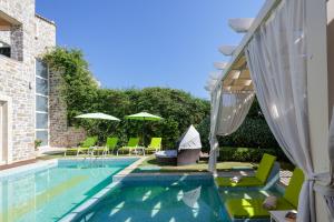 basen z zielonymi leżakami i parasolami w obiekcie Villa Green Mare w mieście Prínos