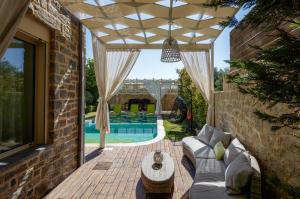 patio z kanapą, stołem i basenem w obiekcie Villa Green Mare w mieście Prínos