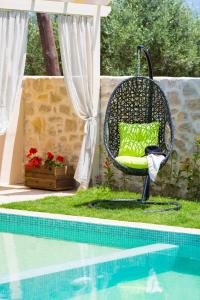 krzesło z zieloną poduszką siedzącą obok basenu w obiekcie Villa Green Mare w mieście Prínos