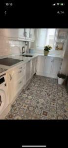 uma cozinha com armários brancos e piso em azulejo em Punta umbria sol y mar em Punta Umbría