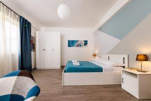 a white bedroom with a bed and a desk at Blue Apartment Messina in Messina