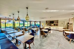 a restaurant with tables and chairs and windows at Kyriad Hotel Meaux in Meaux