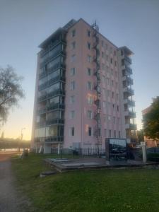a tall pink building with a grass field in front of it at Malminranta in Savonlinna