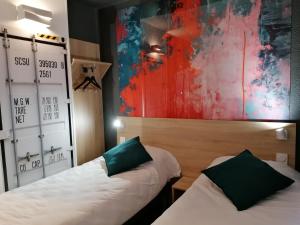 two beds in a room with a painting on the wall at Kyriad Direct Martigues in Martigues