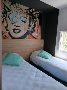 a bedroom with two beds and a painting on the wall at Kyriad Direct Martigues in Martigues