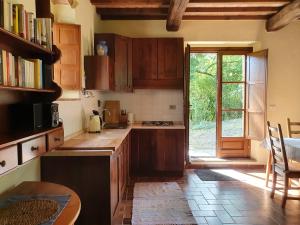 uma cozinha com armários de madeira, uma mesa e uma janela em Agriturismo Palareta em Montecatini Val di Cecina
