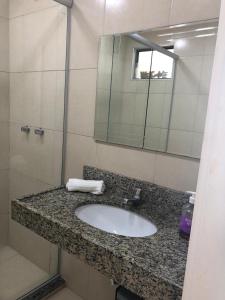 eine Badezimmerablage mit Waschbecken und Spiegel in der Unterkunft Cobertura Duplex Beverly Hills in Aquiraz