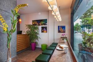 a waiting area of a restaurant with green chairs and plants at SORAT Hotel Berlin in Berlin