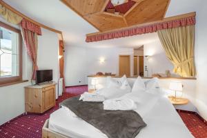 a bedroom with a large white bed with white pillows at Naturhotel Waldheim in Anterivo