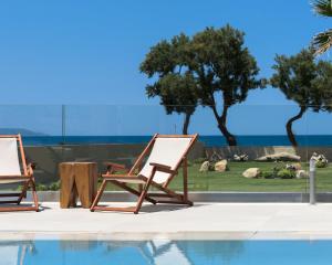 two lounge chairs sitting next to a swimming pool at Artemis Villa, Beachfront Retreat with Heated Pool, By ThinkVilla in Tavronitis +73 photos