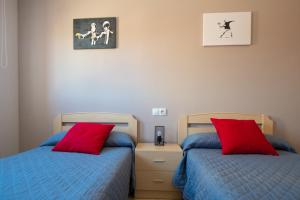 two beds with red pillows in a bedroom at MEQUEDO AVENIDA ZARAGOZA in Alcañiz