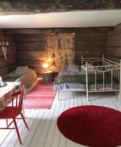 um quarto com 2 camas, uma mesa e um tapete vermelho em Päivin pirtti - Pirttikahvila ja B&B em Luosto