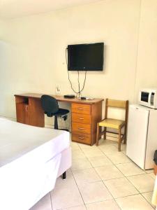 1 dormitorio con escritorio y TV en la pared en Apart Hotel em Brasília - Garvey Park Hotel, en Brasilia
