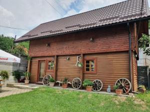 a wooden house with two wagon wheels on it at Pensiunea Carmen in Bucium