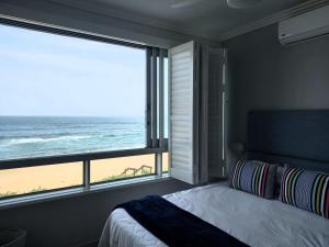 a bedroom with a bed and a view of the beach at Modern & Luxurious Beachfront Villa in Ballito