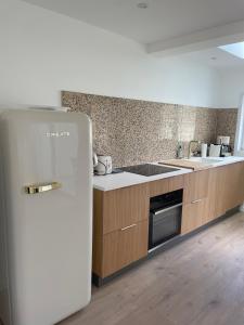 a white refrigerator in a kitchen with wooden cabinets at Villa Poirabelle in Wimereux