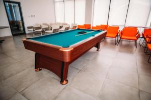 a pool table in a room with orange chairs at Relaxing villa with access to pool and beach in Ras al Khaimah