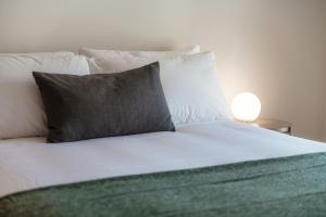 - un lit avec un oreiller et une lampe sur une table dans l'établissement Minusio Apartment by Quokka 360 - bright and modern flat with balcony, à Minusio