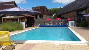a swimming pool with chairs and an umbrella at Domaine de Vaulatour. in Payzac