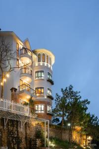 a large white building with balconies on the side of it at De La Sol Villa Dalat in Da Lat