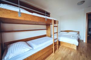 two bunk beds in a room with wooden floors at Pohorje Village Wellbeing Resort - Forest Apartments Videc in Hočko Pohorje