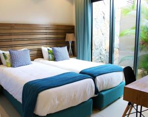 1 dormitorio con 2 camas y almohadas azules y blancas en West Coast Marina en Rivière Noire